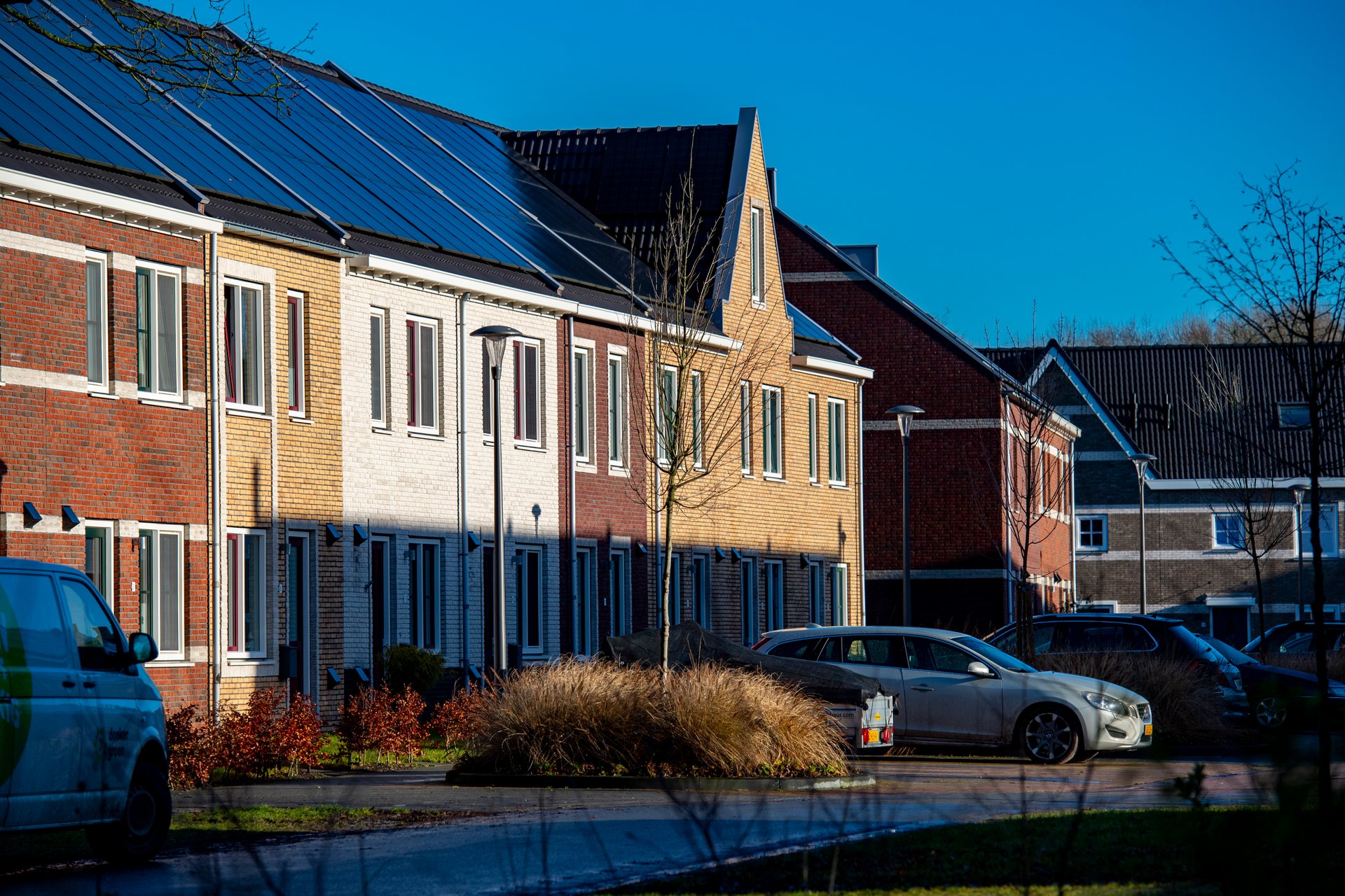 Huizen met zonnepanelen en een auto op de oprit.