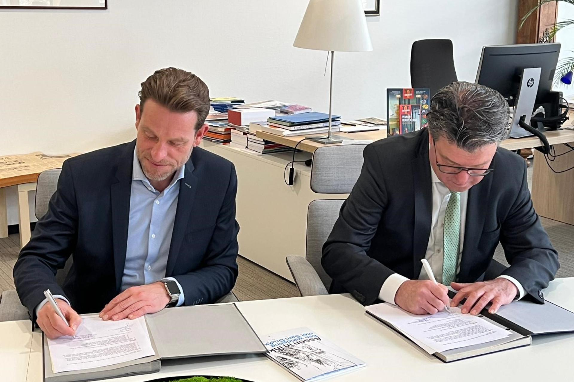 Wethouder Bert Jan ten Oever en Hans Wijnen, lid dagelijkse bestuur WDO Delta, ondertekenen de overeenkomst om de afspraken vast te leggen.